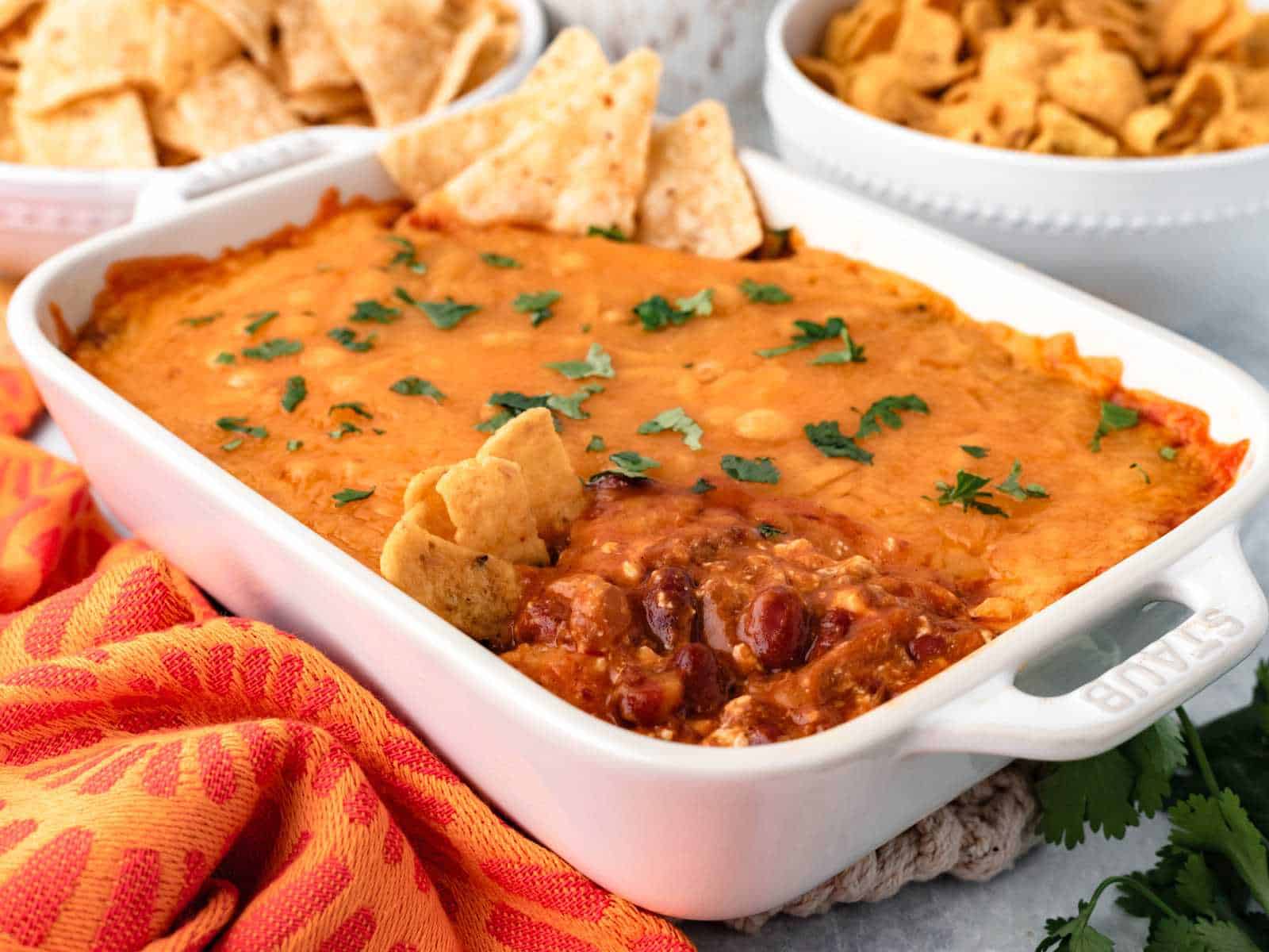 Chili cream cheese dip in a white baking dish with fritos.