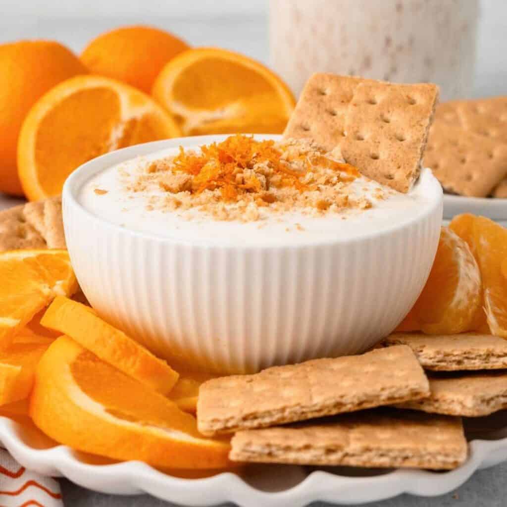 Cottage cheese fruit dip in a white bowl surrounded by oranges.