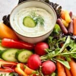 Cottage cheese ranch dip in a white bowl surrounded by colorful veggies.
