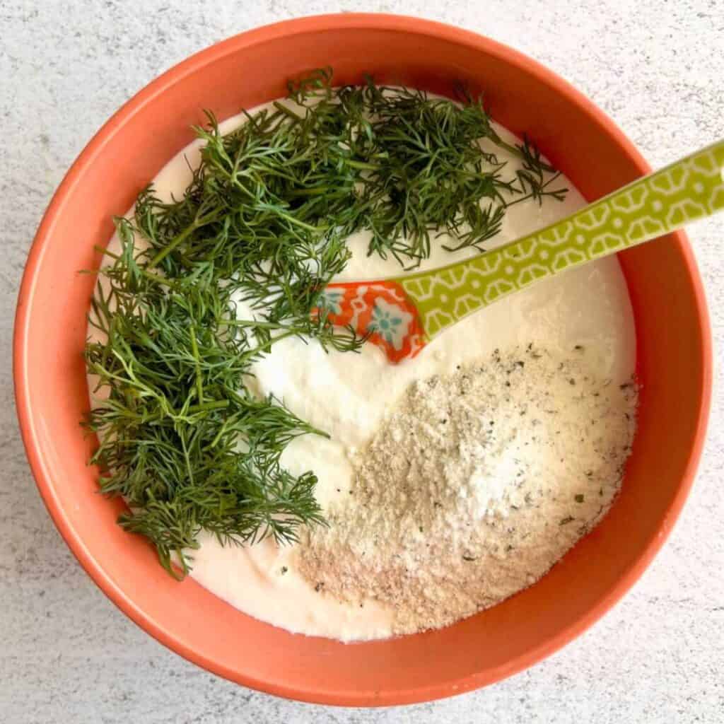 Cottage cheese ranch dip ingredients in a bowl with a spoon.