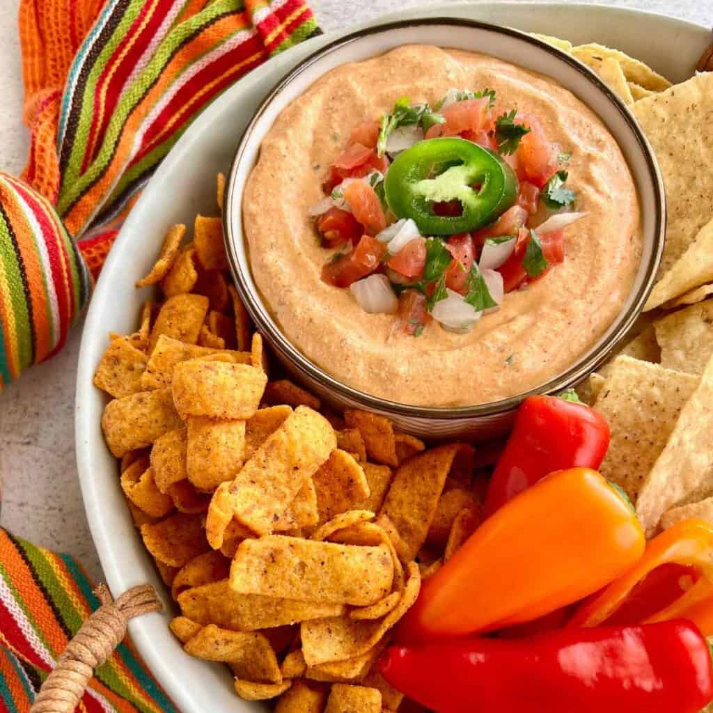 Cottage cheese taco dip in a white bowl with fritos and chips surrounding it.