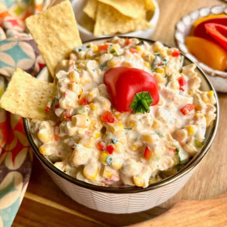 Cold Fiesta Corn Dip in a white bowl with a red pepper on top.