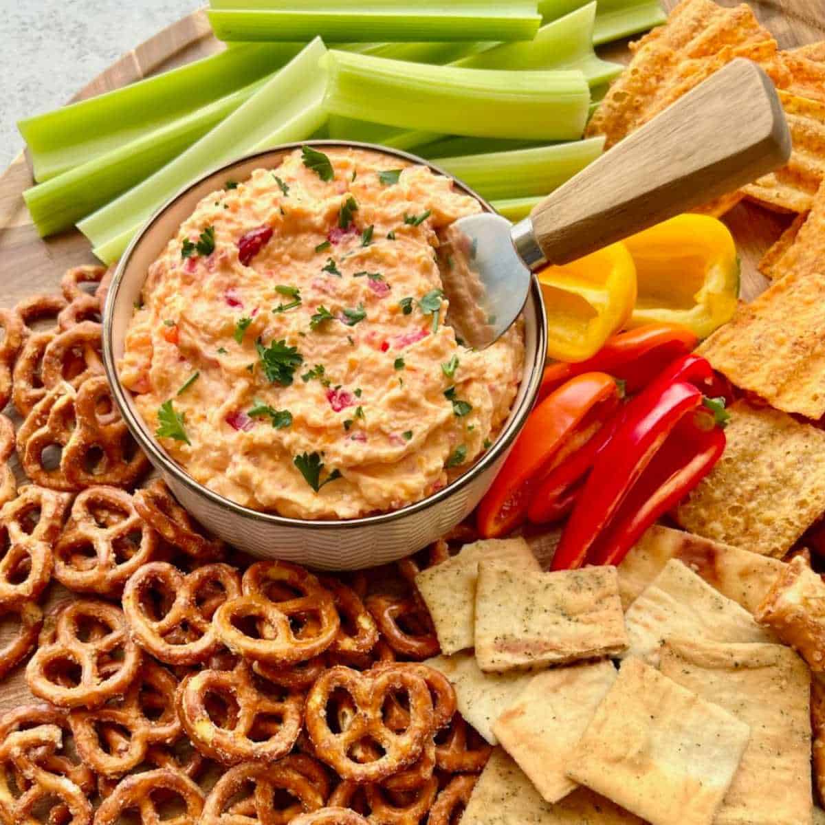 Dish containing homemade pimento cheese surrounded by pretzels and chips.