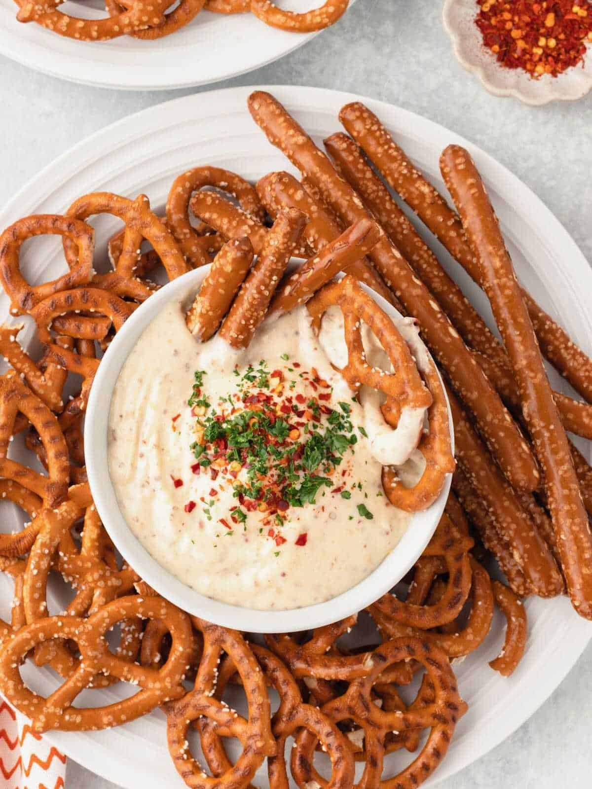Pretzels dipped into a bowl of mustard dip.
