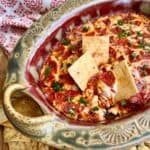 Pepperoni Pizza Dip baked in a pottery dish with crackers dipping into it.