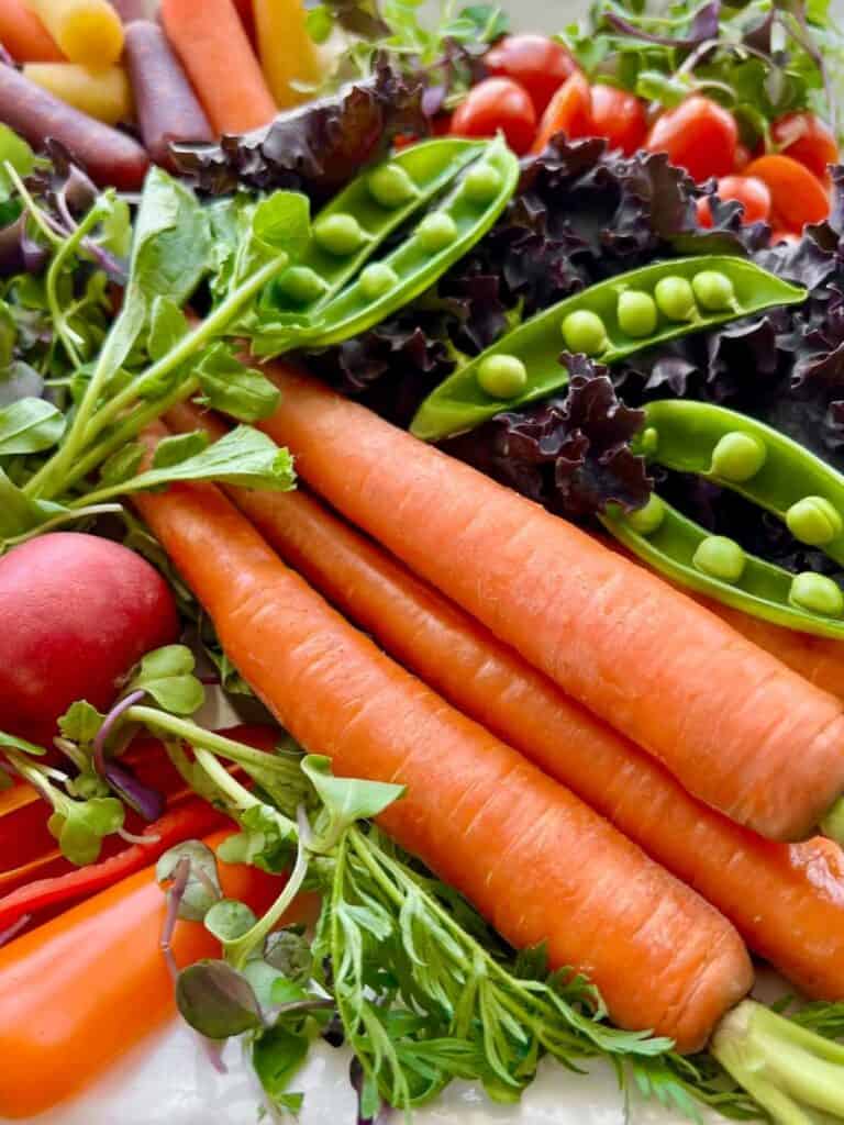 Carrots, peas, beets, and tomatoes on a platter.
