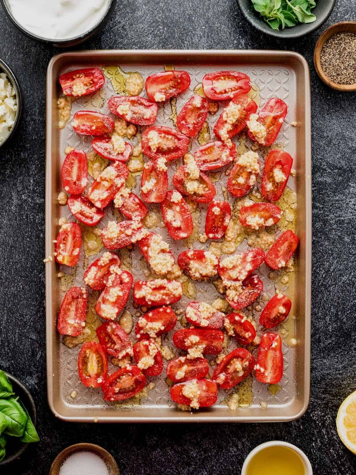 Roasted cherry tomatoes with garlic and olive oil on a sheet pan.