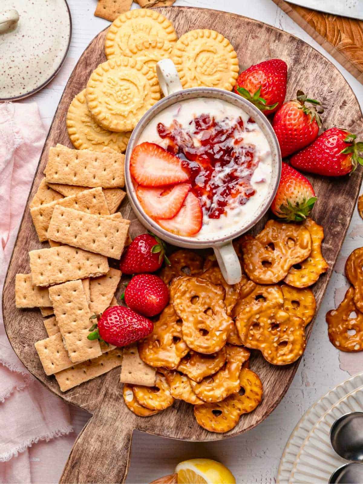 Strawberry cheesecake dip board with crackers, pretzel chips, and strawberries.