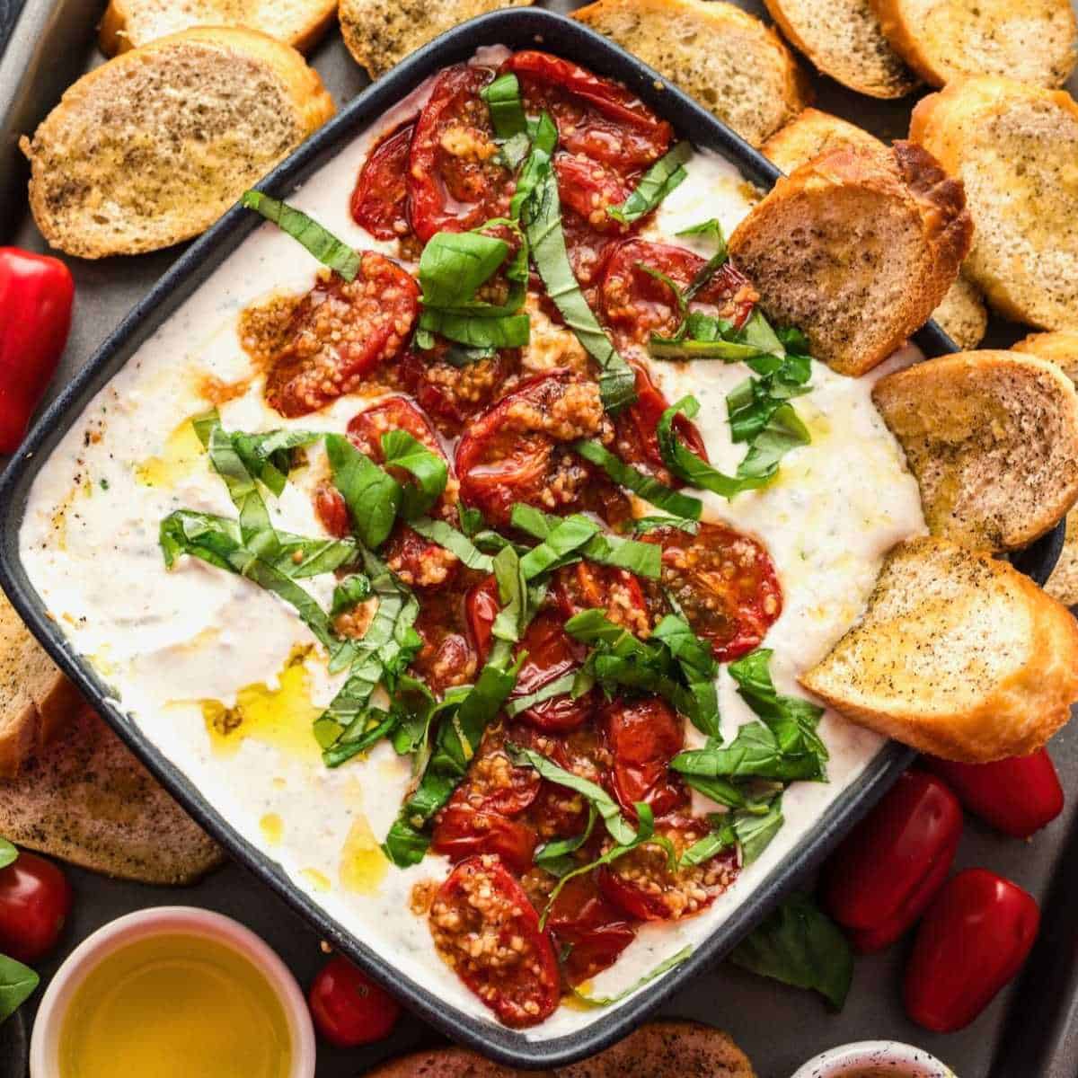 Bowl of whipped feta with roasted tomatoes on top.