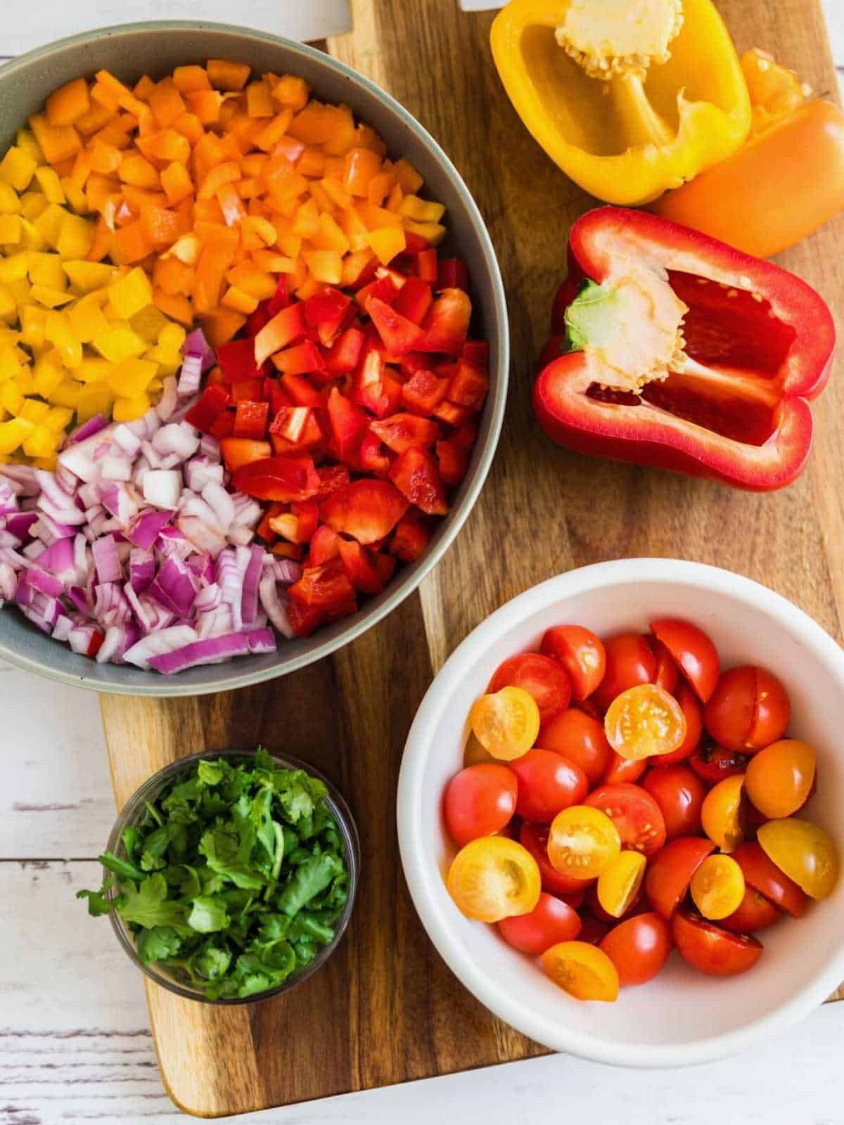 Colorful red, orange and yellow peppers chopped on a wooden board.