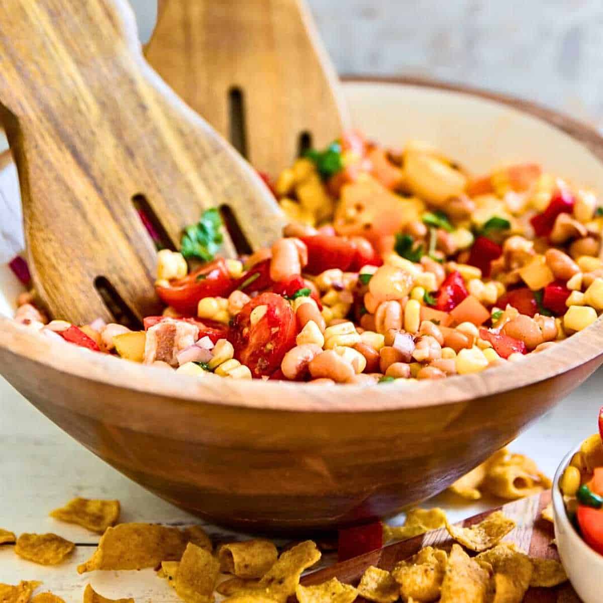 Salad forks mixing Cowboy Caviar together in a large wooden bowl.