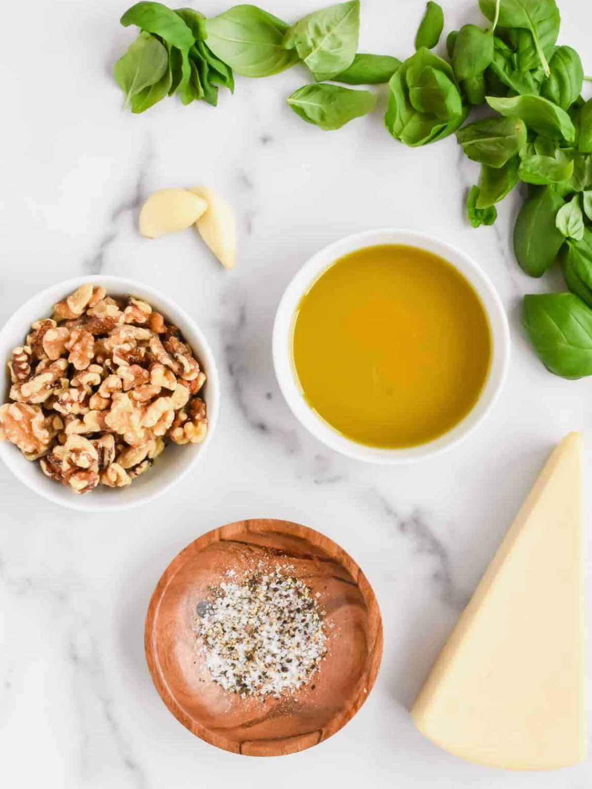 Ingredients needed to make basil pesto with walnuts.