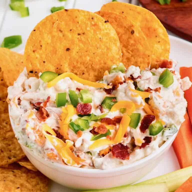 Tortilla chips dipping into a white bowl of Million Dollar Dip.