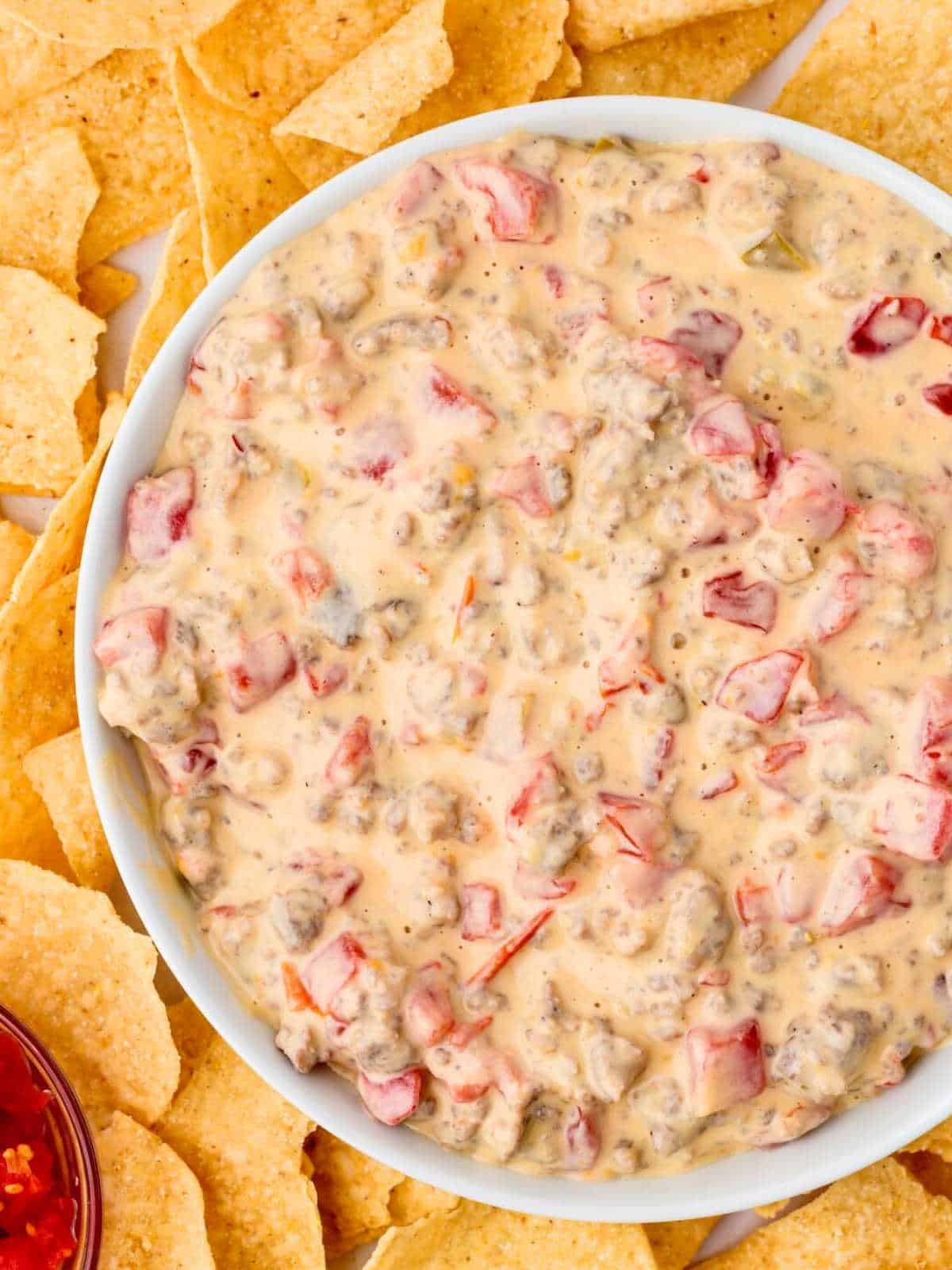White bowl filled with sausage and cream cheese, RoTel and Velveeta.