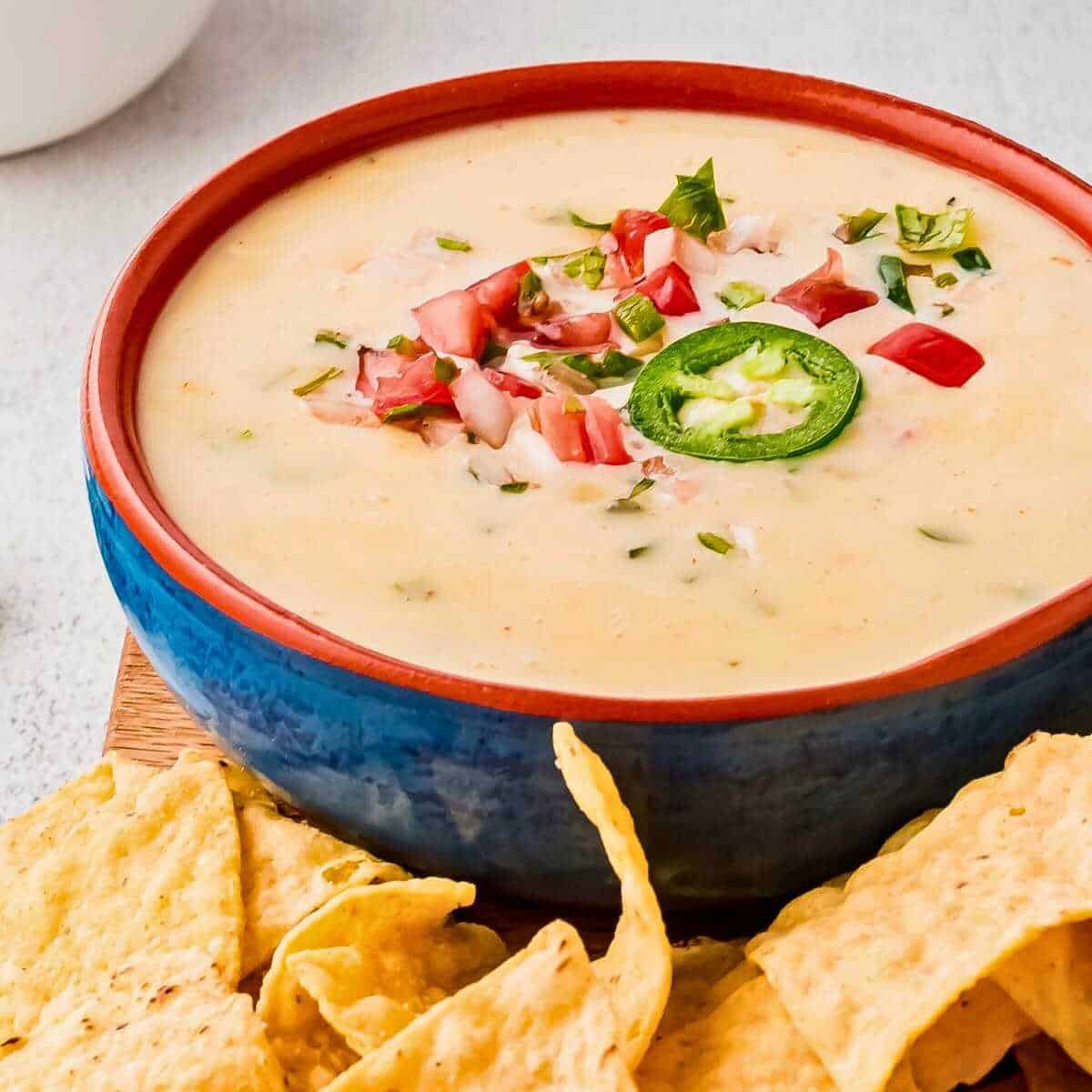 Crockpot white queso dip surrounded by tortilla chips.