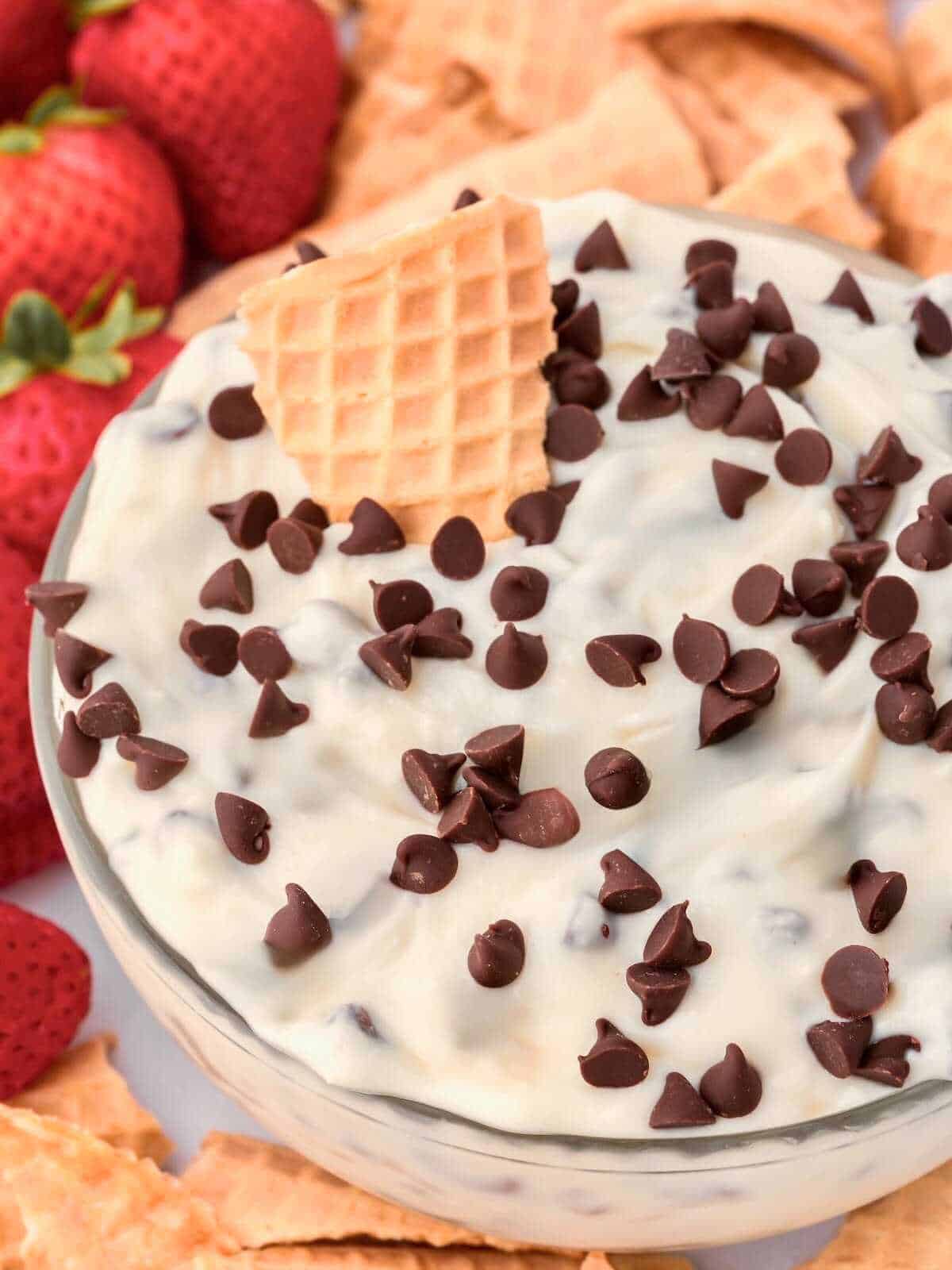 Broken waffle cone piece dipping into cannoli dip.