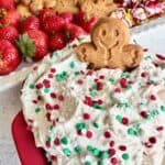 Gingerbread man sitting on top of a red bowl of Little Debbie Christmas tree dip.