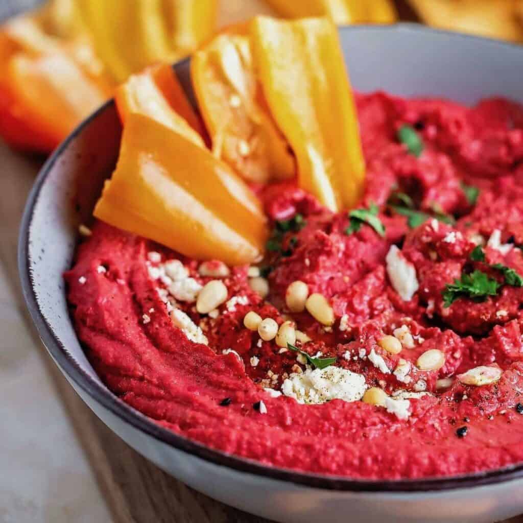 Roasted Red Beet Hummus with toppings and peppers as dippers.