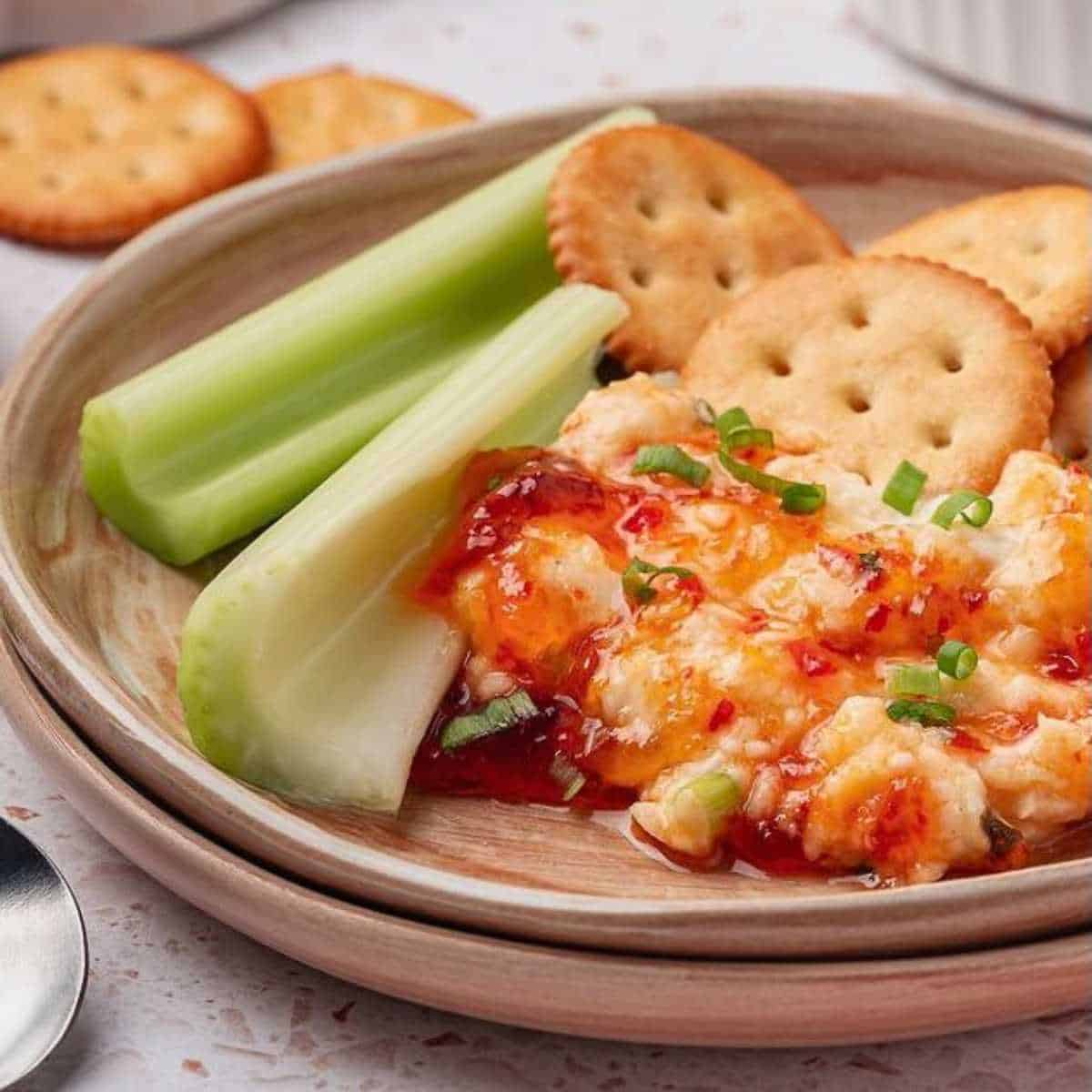 Pepper Jelly Cream Cheese Dip on a plate with celery and Ritz crackers.