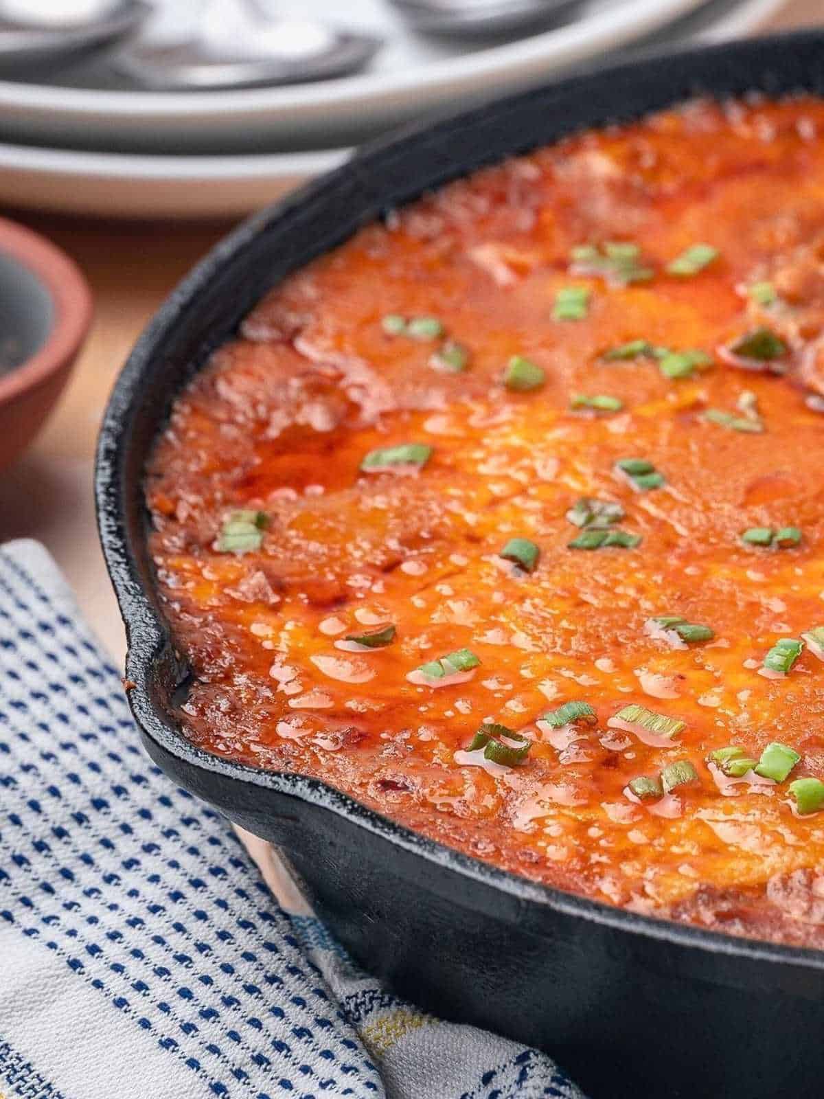 Cheese melted on top of sloppy joe dip in a cast iron skillet.
