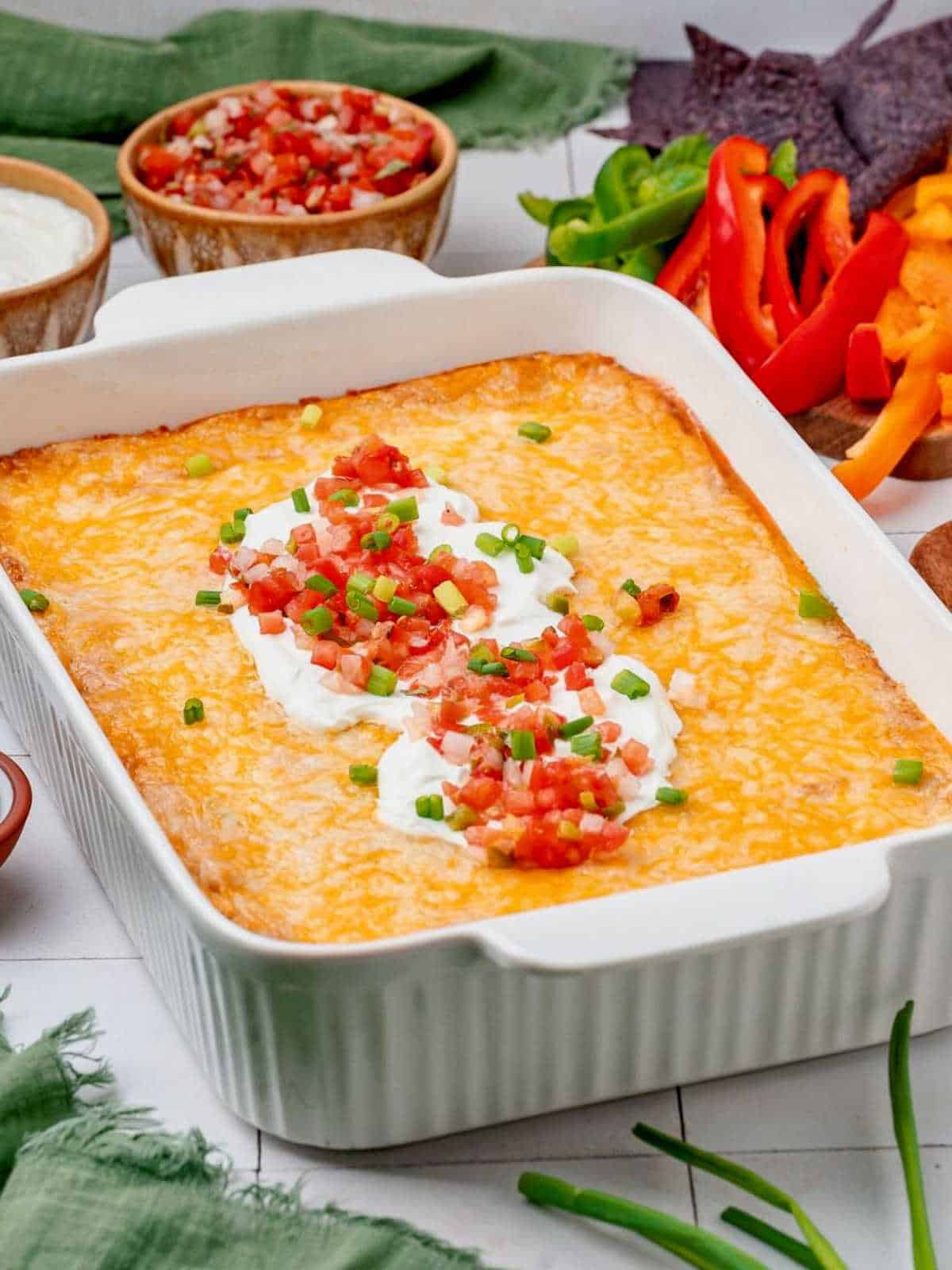 Sour cream and pico de gallo topping a casserole dish of Texas trash dip.