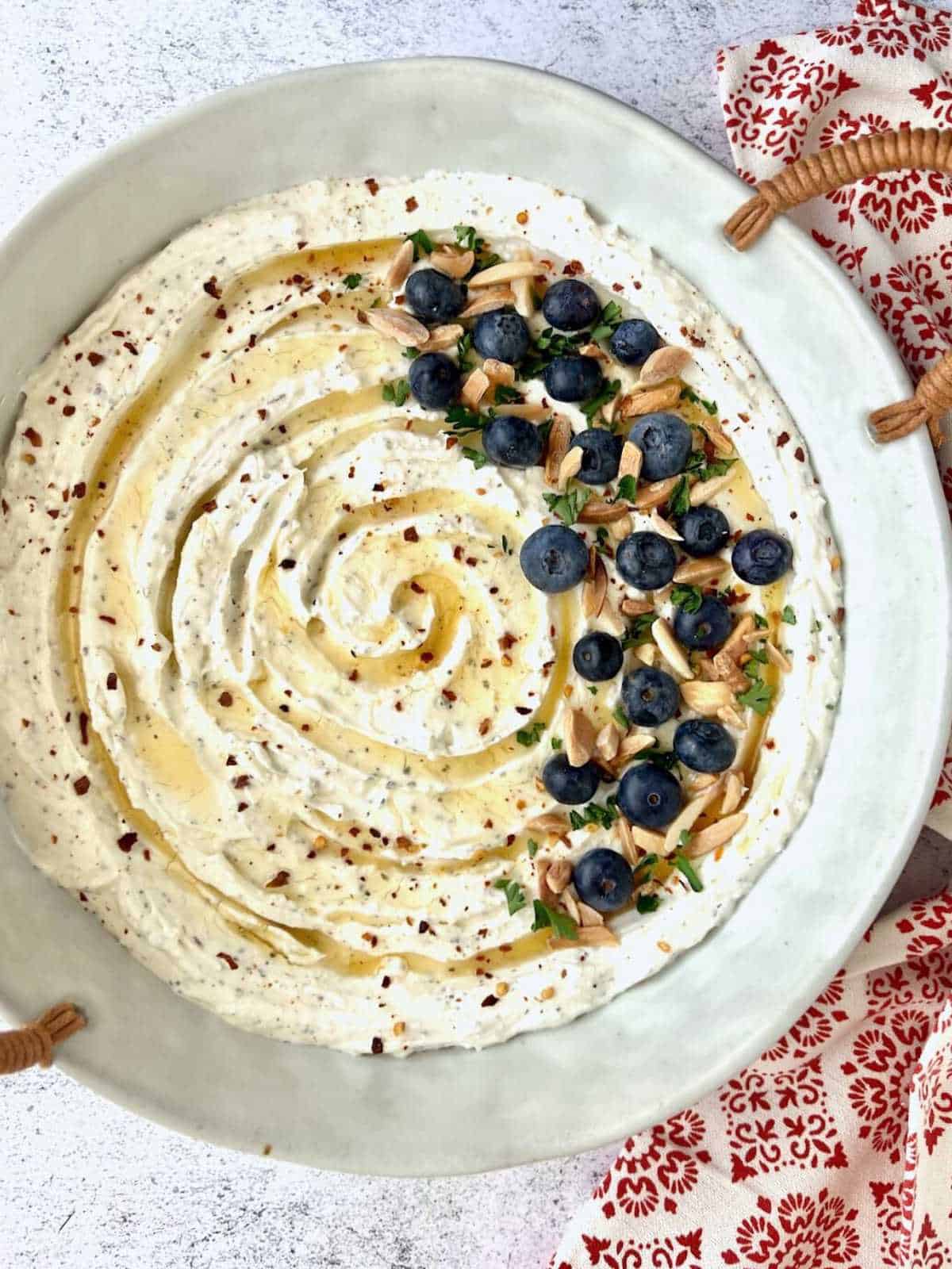 Blueberries on the side of a dish of whipped honey feta cheese.