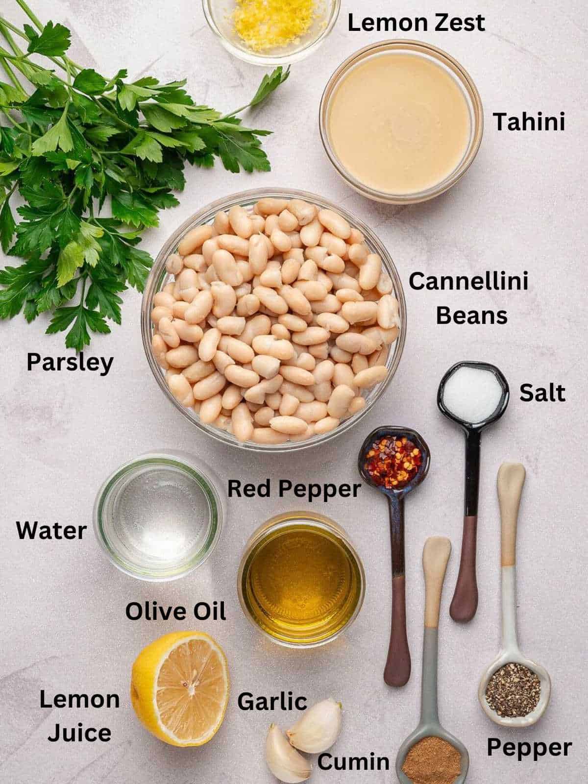 Ingredients needed to make white bean dip in small containers.