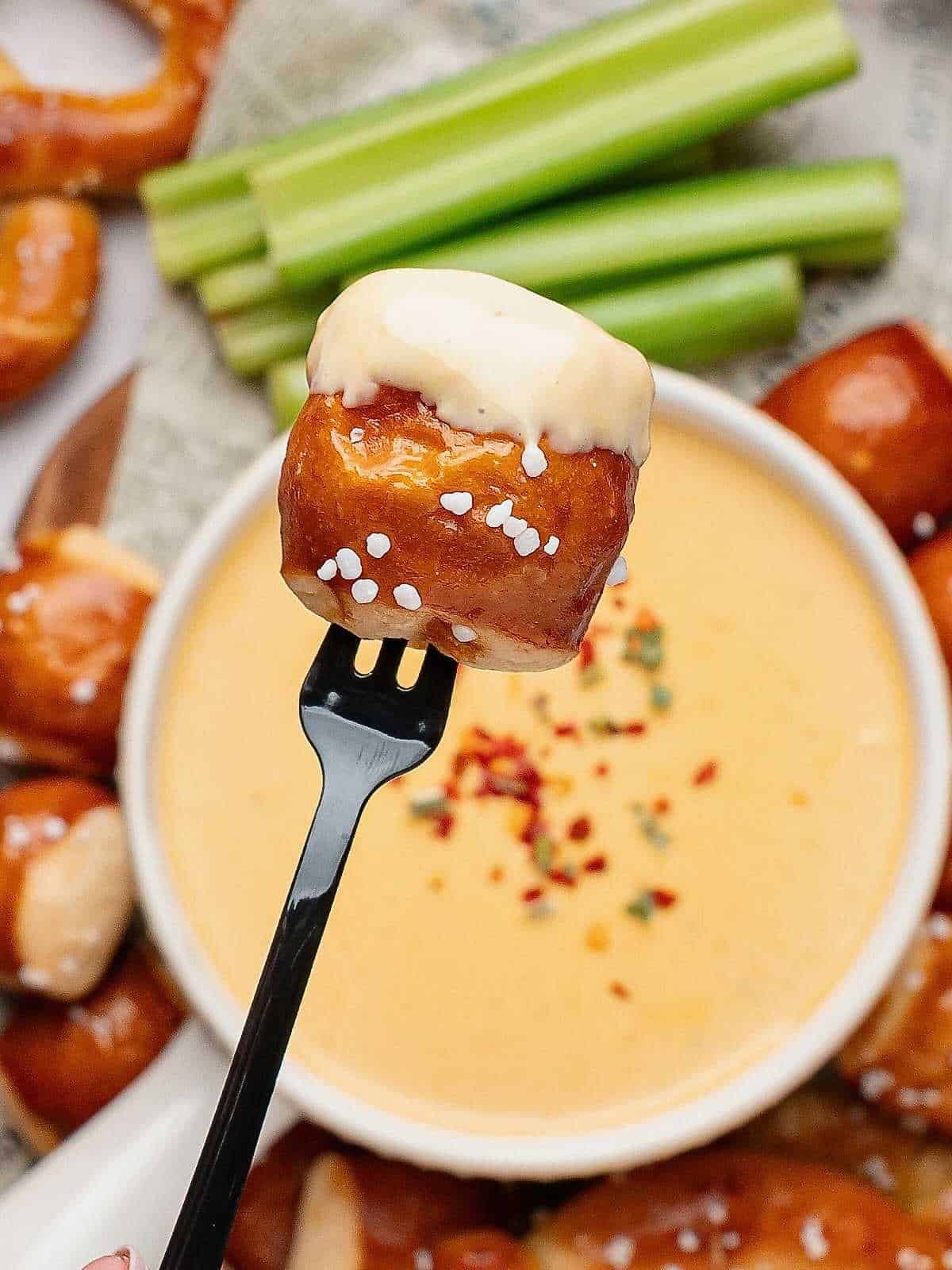 Pretzel Bite dipped in beer cheese on a tiny fork.