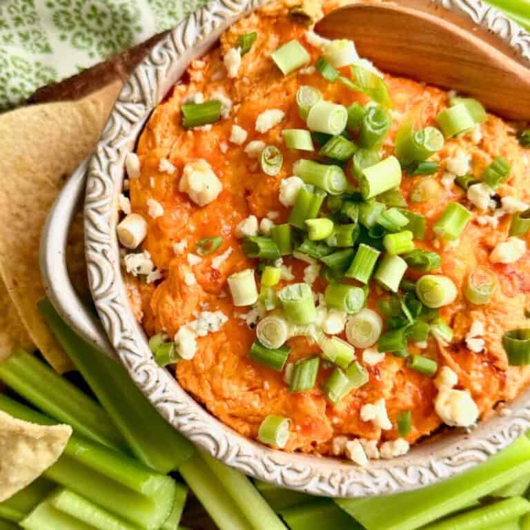 Crockpot Buffalo Chicken Dip in a dish with a spoon surrounded by celery.