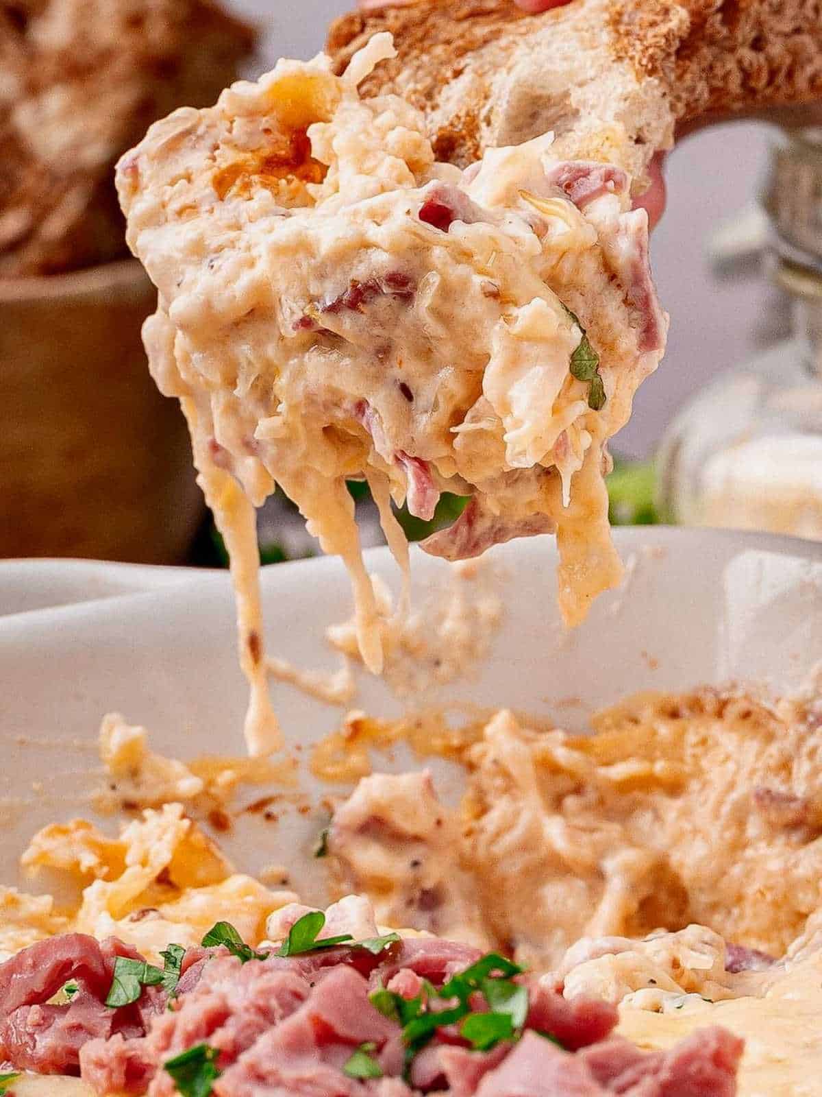 Rye bread dipped into a dish of reuben dip.