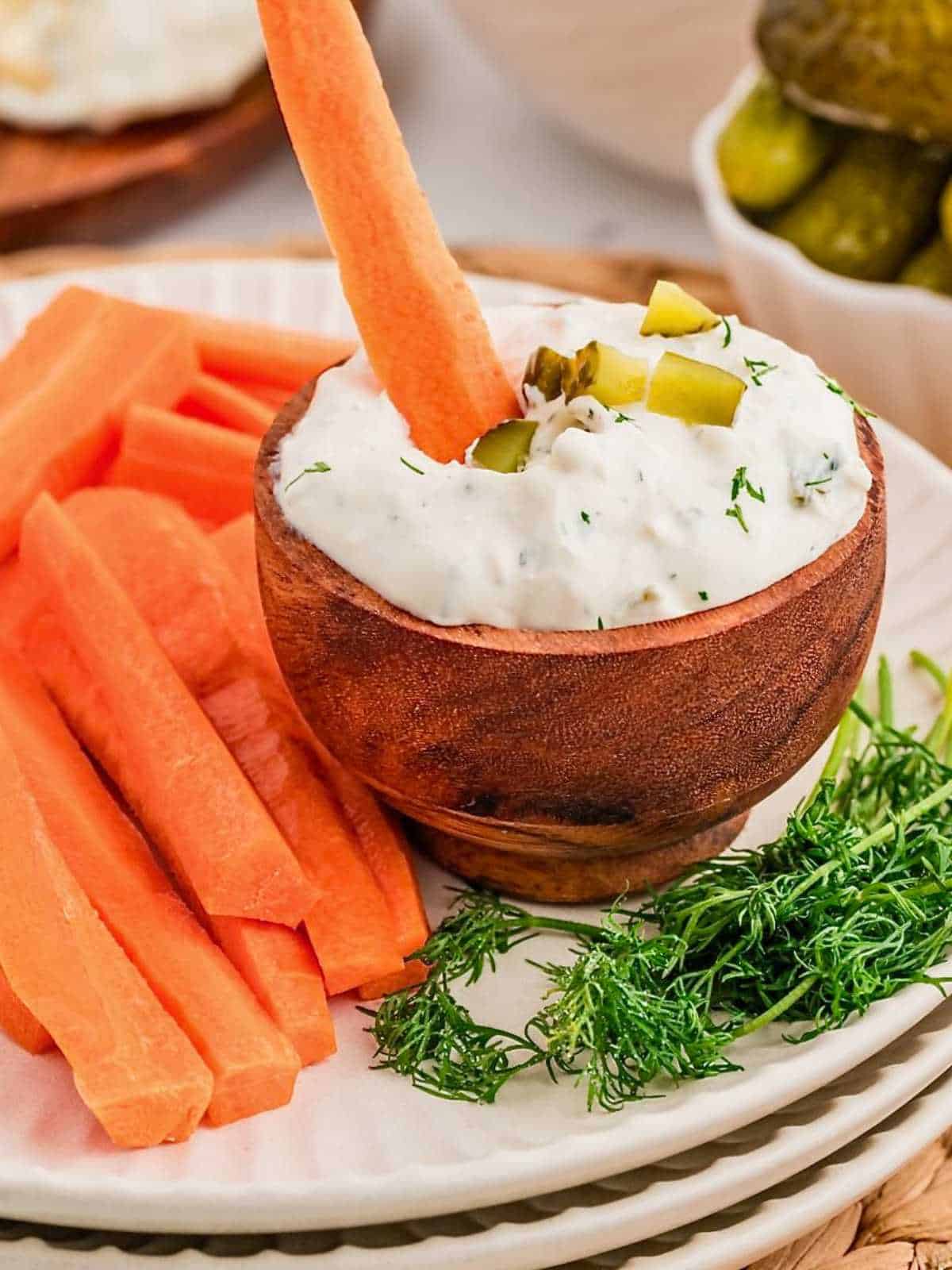 Carrot stick dipping into dill pickle dip.