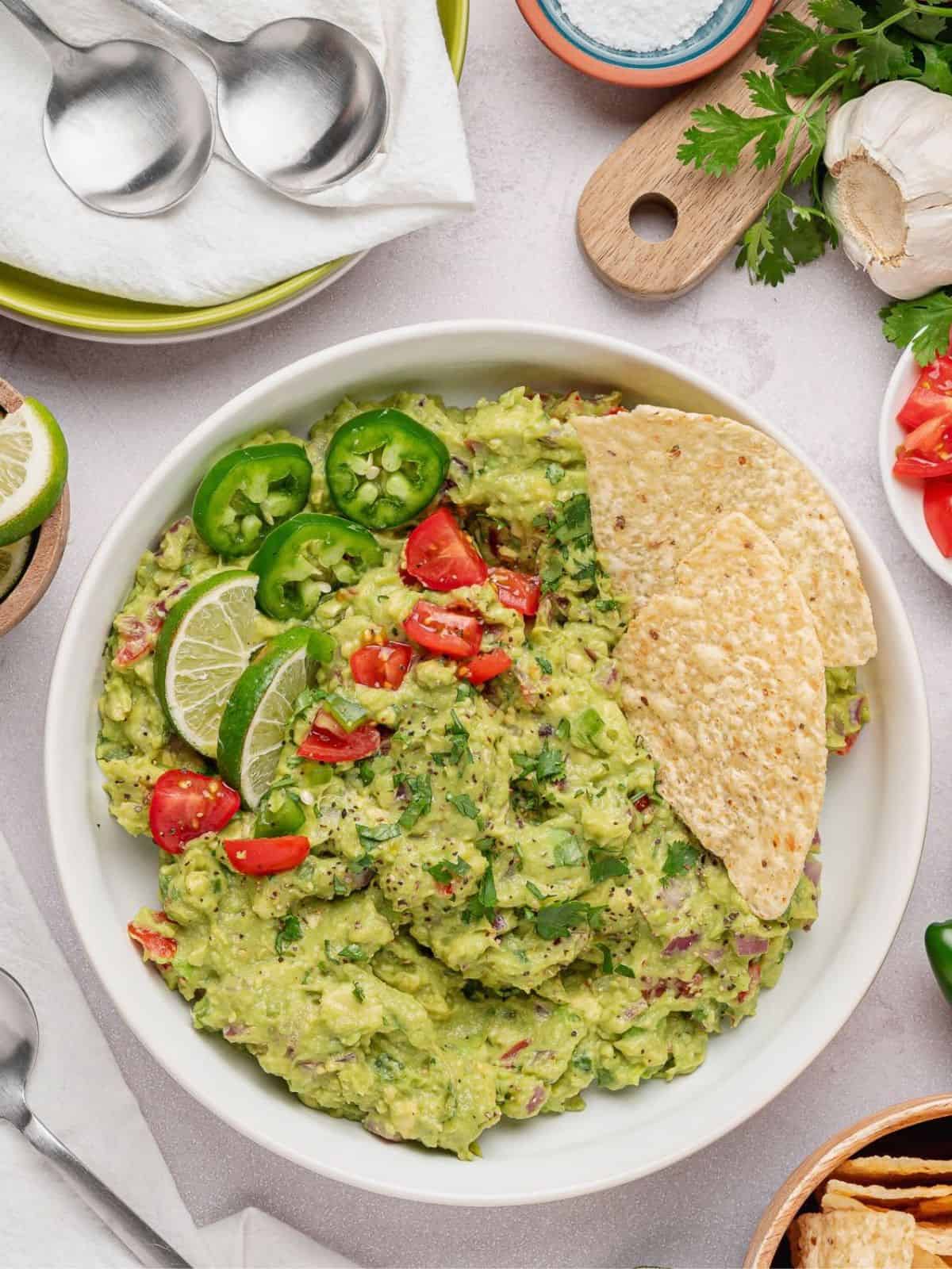 Guacamole surrounded by plates and veggies.