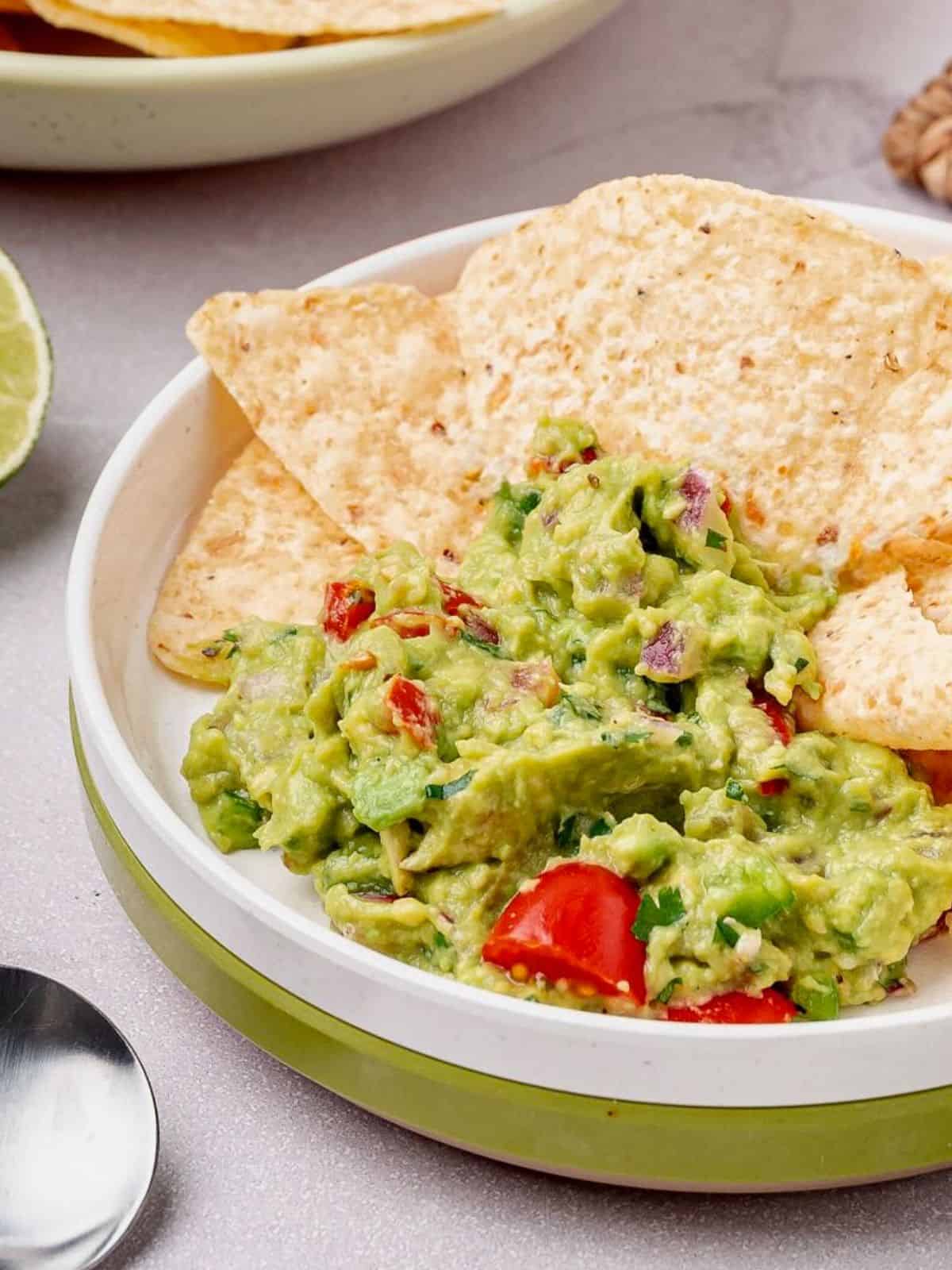 Chips dipping into a big bowl of the best guacamole.