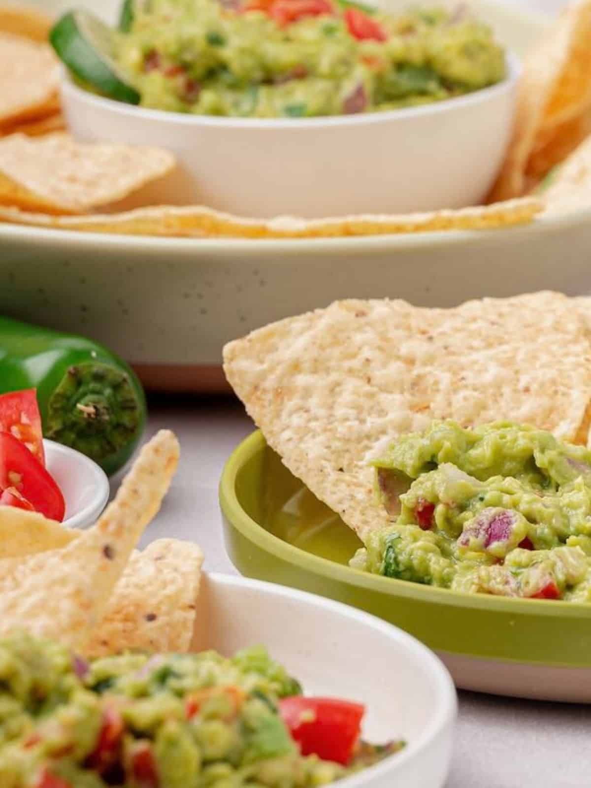 Bowls of guacamole with chips.