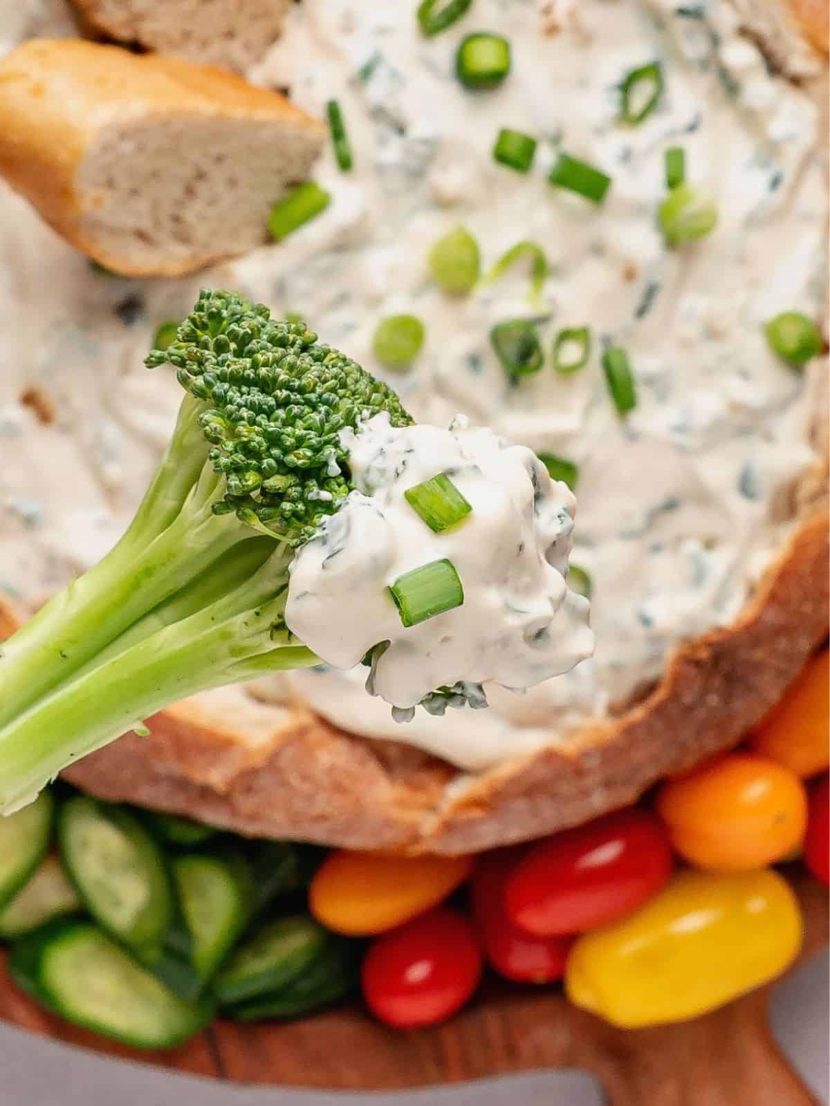 Piece of broccoli dipping into spinach dip.