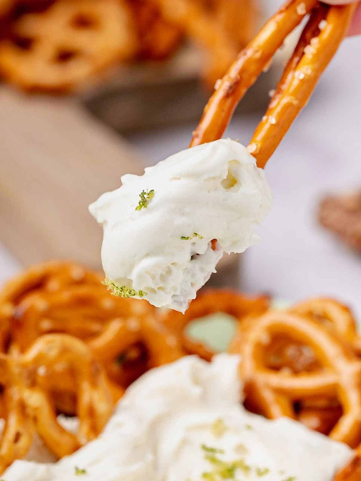 Two pretzel rods holding up a scoop of dip.