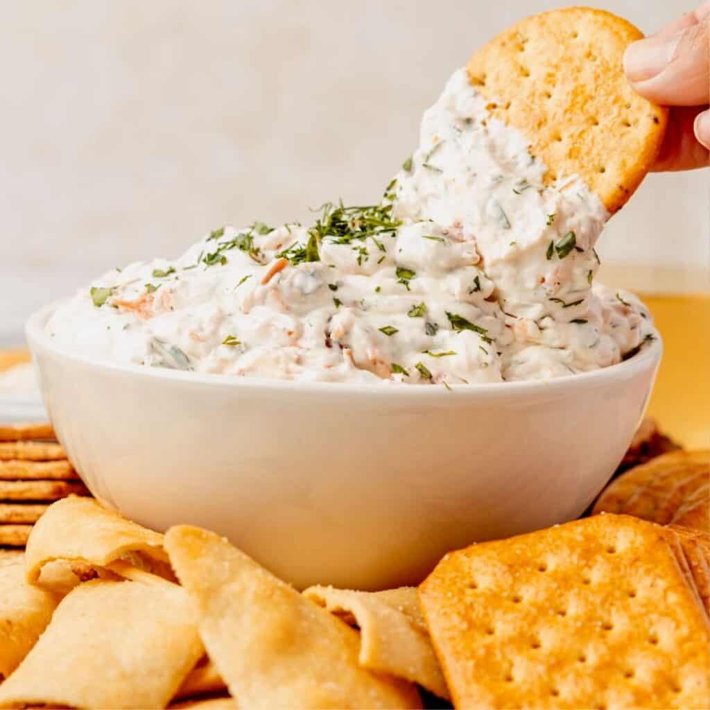 Smoked salmon dip being dipped into with a cracker.