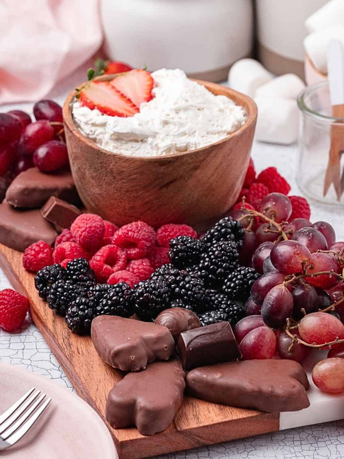 Dessert board with raspberries, blackberries and grapes and marshmallow fruit dip in the middle.