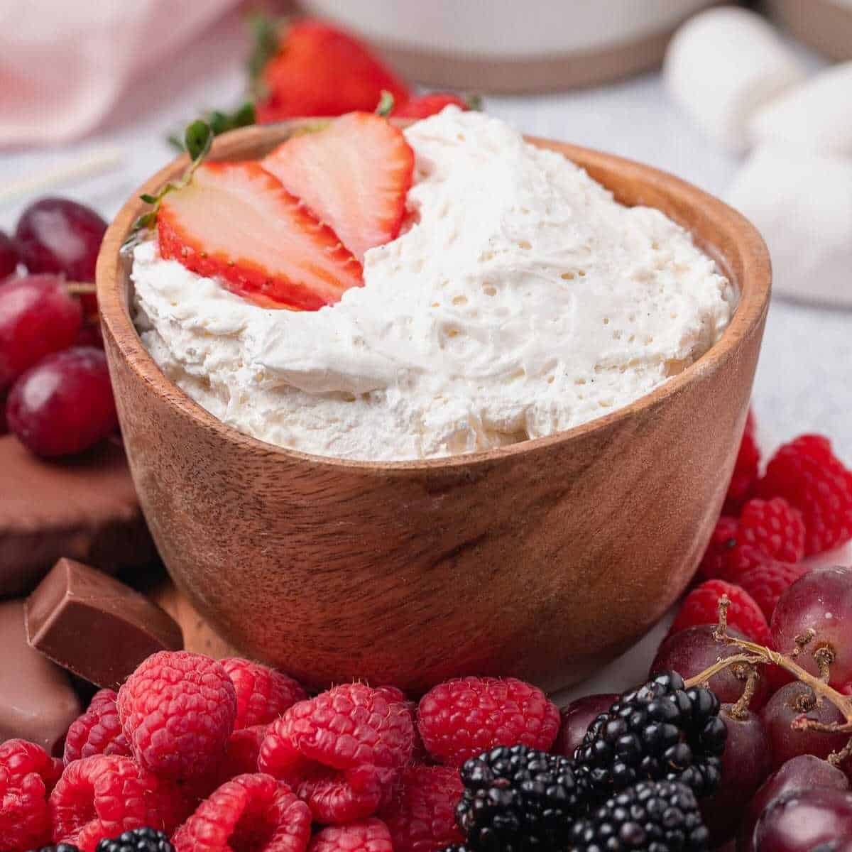 Bowl of Marshmallow Fluff Fruit Dip surrounded by berries.