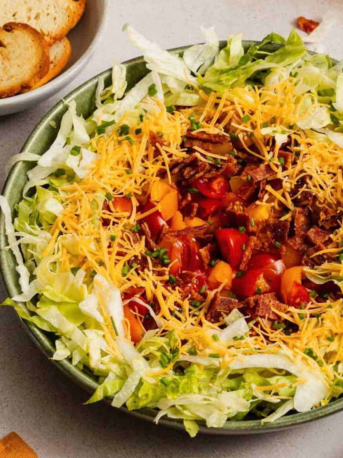 BLT Dip with bacon, lettuce, tomatoes and cheese in a green plate.