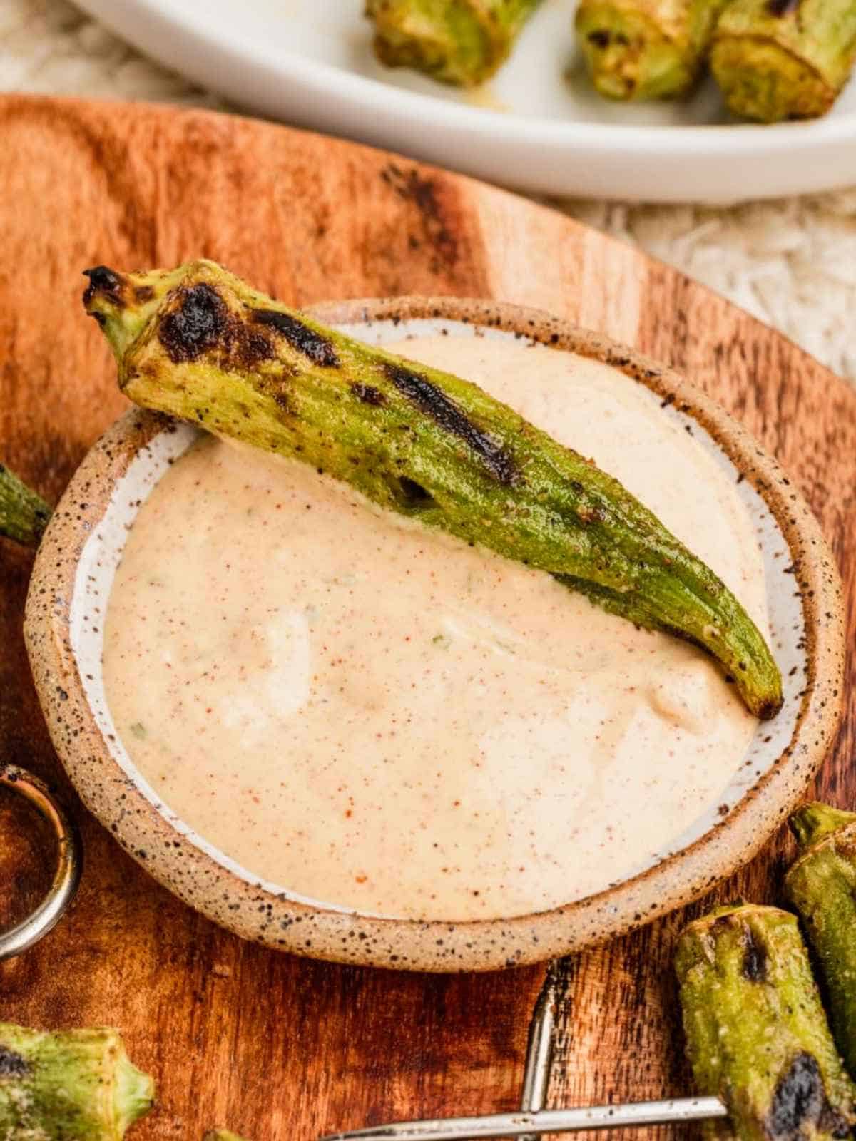 Grilled okra sitting on top of Cajun dipping sauce.