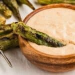 Grilled okra sitting on top of a brown bowl of Cajun Dipping Sauce.
