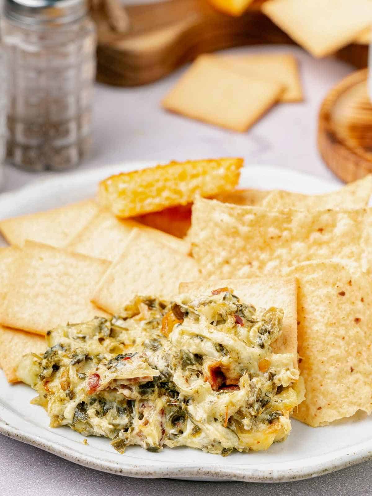 Scoop of dip on the side of a plate with chips and pita.