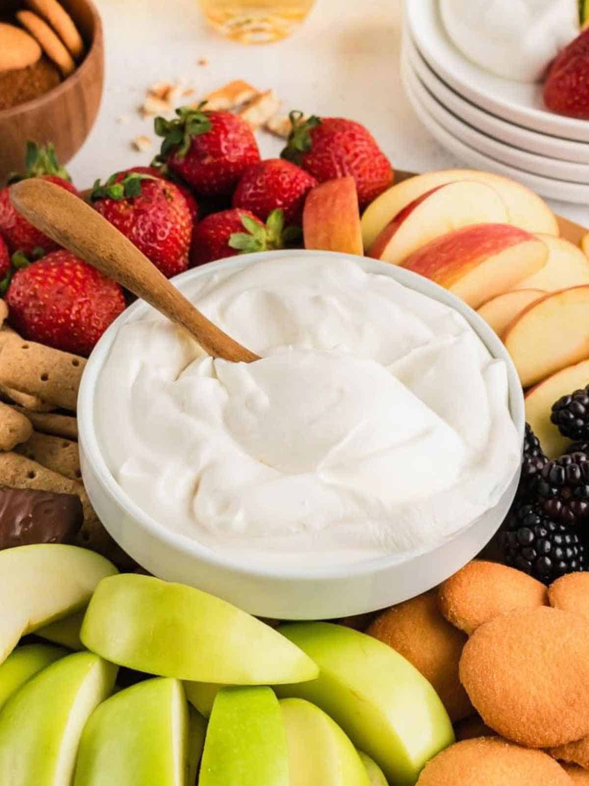 A bowl of Cool Whip Fruit Dip with fruit and cookies as dippers.