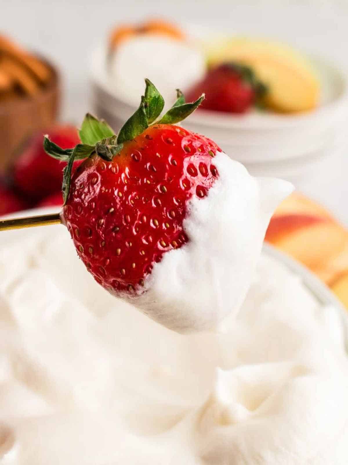 Fresh strawberry dipping into cool whip fruit dip.
