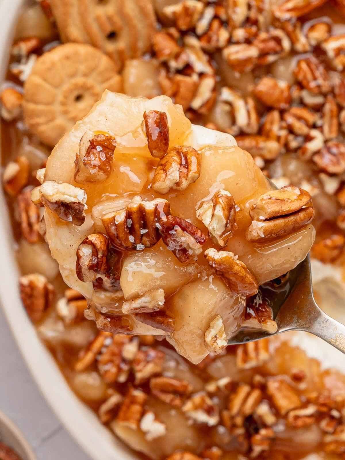 Apples and pecans being held up by a spoon.