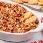 Cookies dipping into Caramel Apple Dip with pecans on top.