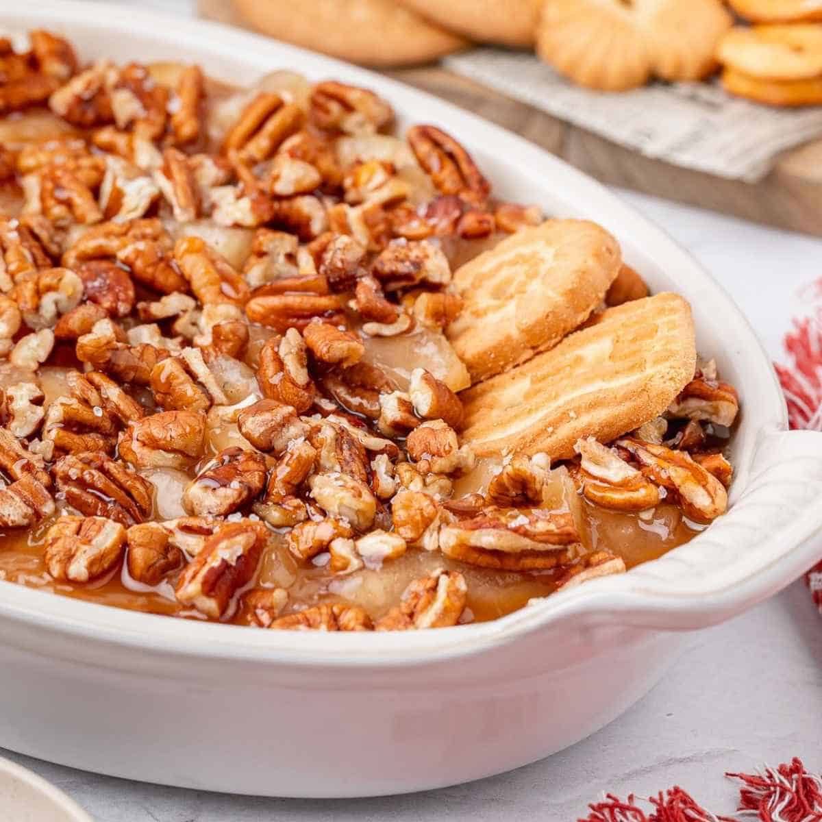 Cookies dipping into Caramel Apple Dip with pecans on top.