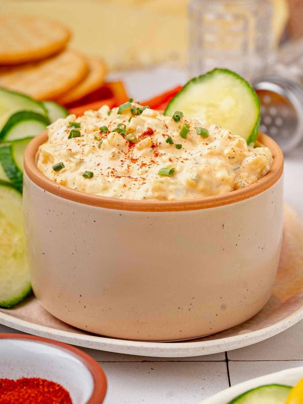 Brown bowl filled with humpty dumpty dip and cucumbers.