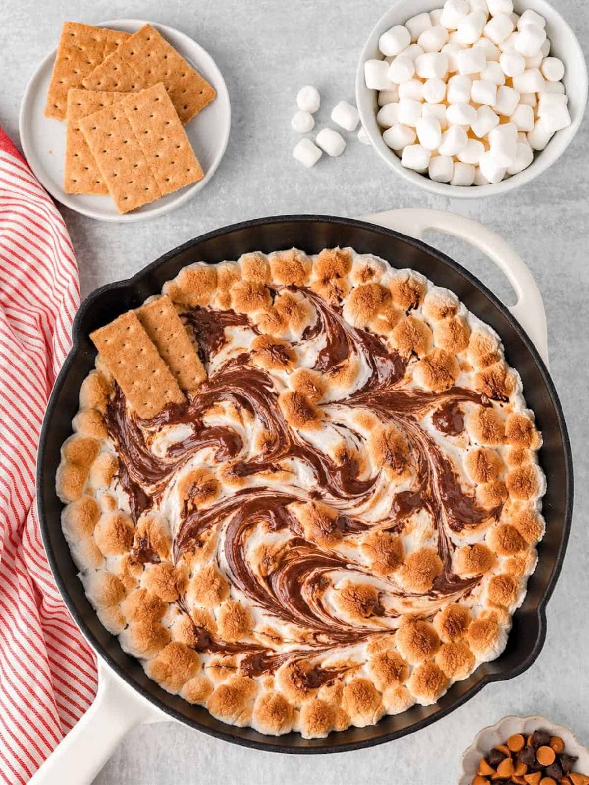 Swirls of chocolate, butterscotch and toasted marshmallows create s'mores dip in a cast iron skillet.